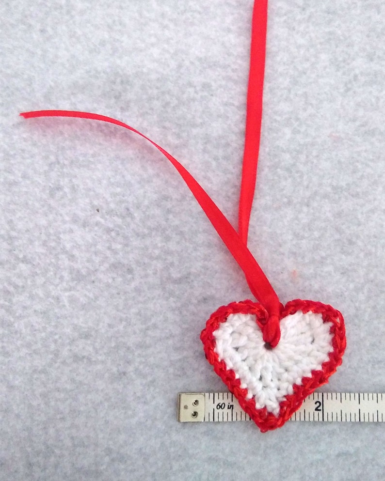 White crochet valentine heart trimmed with red sparkly sequin trim and a satin ribbon. Sweet little holiday gift idea for someone you love. image 3