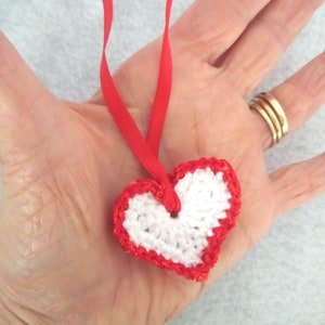 White crochet valentine heart trimmed with red sparkly sequin trim and a satin ribbon. Sweet little holiday gift idea for someone you love. image 2