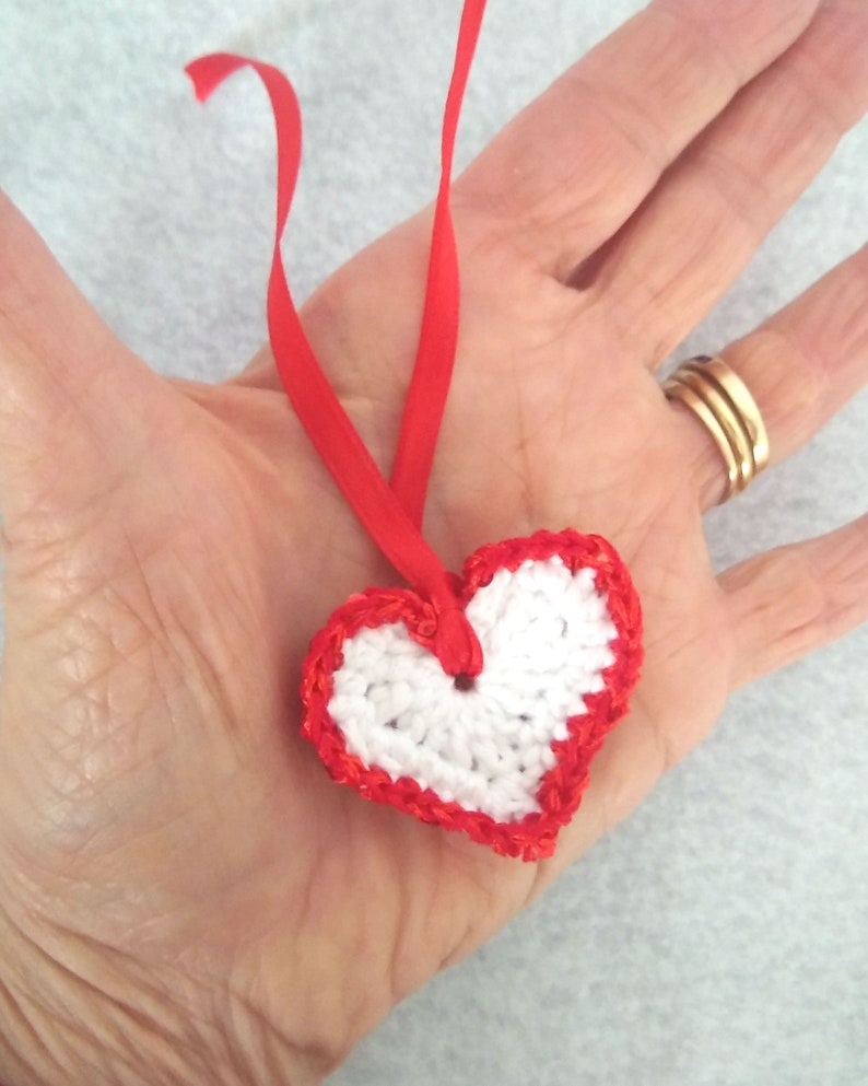 White crochet valentine heart trimmed with red sparkly sequin trim and a satin ribbon. Sweet little holiday gift idea for someone you love. image 2