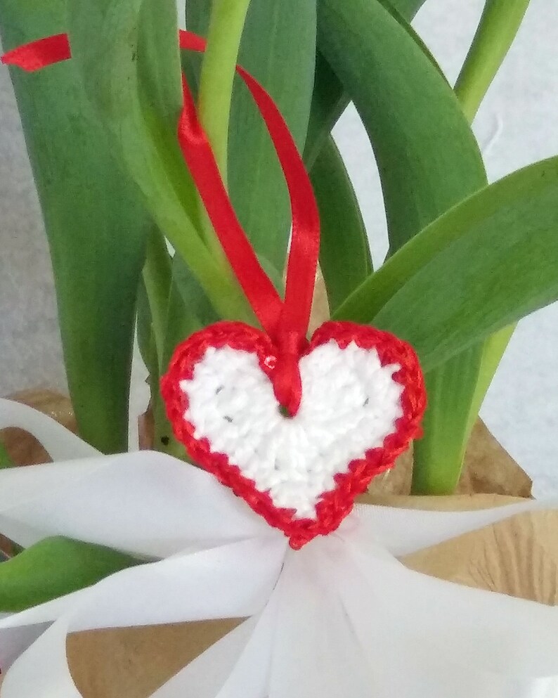 White crochet valentine heart trimmed with red sparkly sequin trim and a satin ribbon. Sweet little holiday gift idea for someone you love. image 1