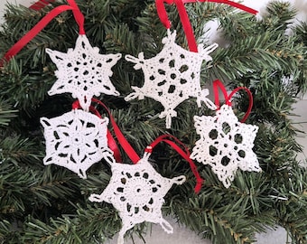 Set of 4 white crochet snowflakes with silvery accents.