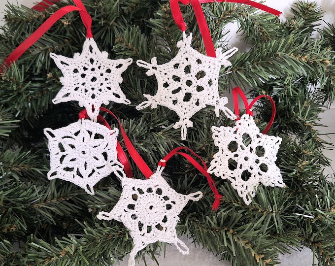 Set of 4 white crochet snowflakes with silvery accents.