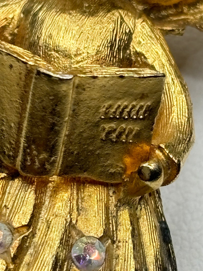 Pu&ograve; includere: Figurina di angelo dorata che tiene un libro con l'iscrizione "Grandma's Girl". L'angelo indossa un abito fluido con strass.