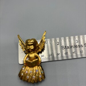 Pu&ograve; includere: Figurina di angelo dorata che tiene un libro con un vestito scintillante. L'angelo &egrave; alto circa 5 cm.