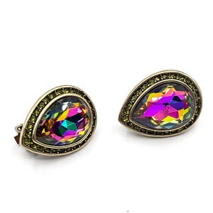 May include: A pair of teardrop-shaped clip-on earrings. Each earring has a large, iridescent, multi-coloured crystal centre stone, surrounded by a border of small, green crystals. The earrings have a gold-toned metal setting.