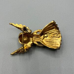 Pu&ograve; includere: Spilla a forma di angelo dorata con un design dettagliato. Il retro della spilla ha uno spillo e una piccola iscrizione che recita "CR1110".