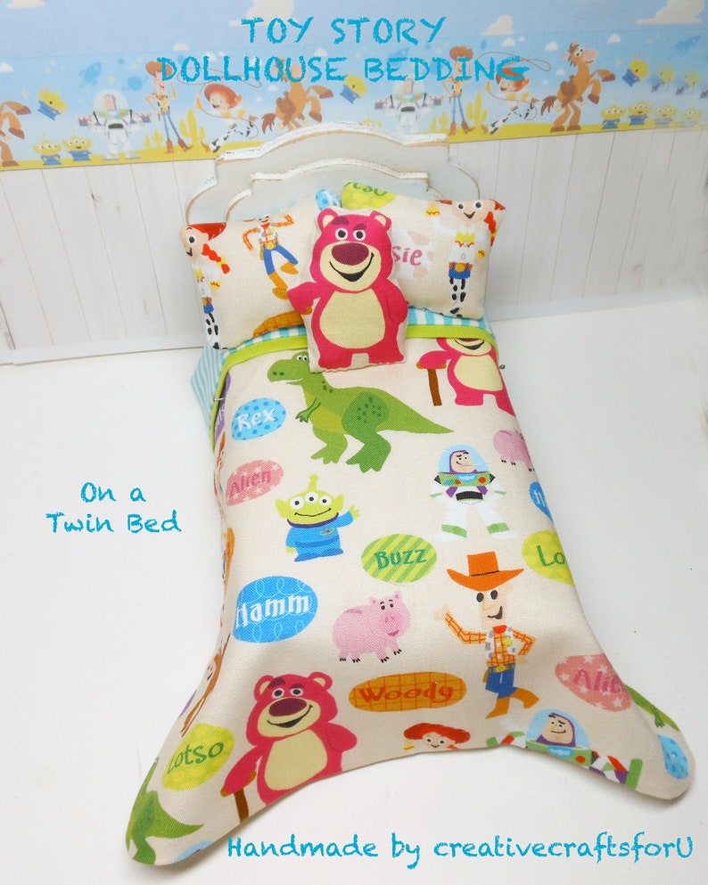 May include: Toy Story dollhouse bedding set with a white twin bed, a white and blue checkered pillow, a red pillow with a bear face, and a white comforter with a colorful Toy Story character print. The comforter features characters like Woody, Buzz Lightyear, Rex, and Hamm.