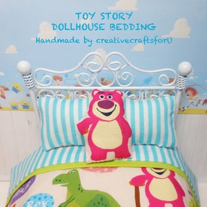May include: Toy Story dollhouse bedding set with a white metal bed frame, blue and white striped pillows, and a pink and yellow  'Lotso' bear pillow. The bedding features a green dinosaur and a pink 'Lotso' bear on a white background.