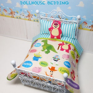 May include: White dollhouse bed with a white metal frame and a Toy Story themed bedding set. The bedding features a white background with colorful characters from the movie, including Buzz Lightyear, Woody, and Jessie. The pillow is pink with a smiling bear face.
