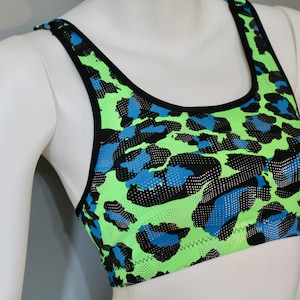 May include: A black, green, and blue leopard print sports bra with a scoop neck and racerback straps.