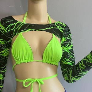 May include: A neon green bikini top and matching tie-up bottoms are paired with a black long-sleeved top featuring a neon green lightning bolt design. The outfit is designed for a bold, eye-catching look.