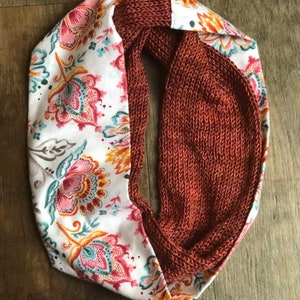 May include: A reversible scarf with a rust-colored knitted side and a white side with a floral pattern.
