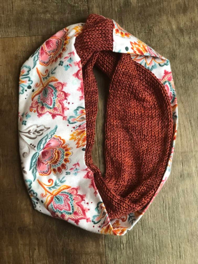 May include: A reversible scarf with a rust-colored knitted side and a white side with a floral pattern.
