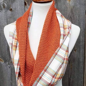May include: A reversible scarf with a knitted orange side and a plaid side with orange, white, and blue accents.