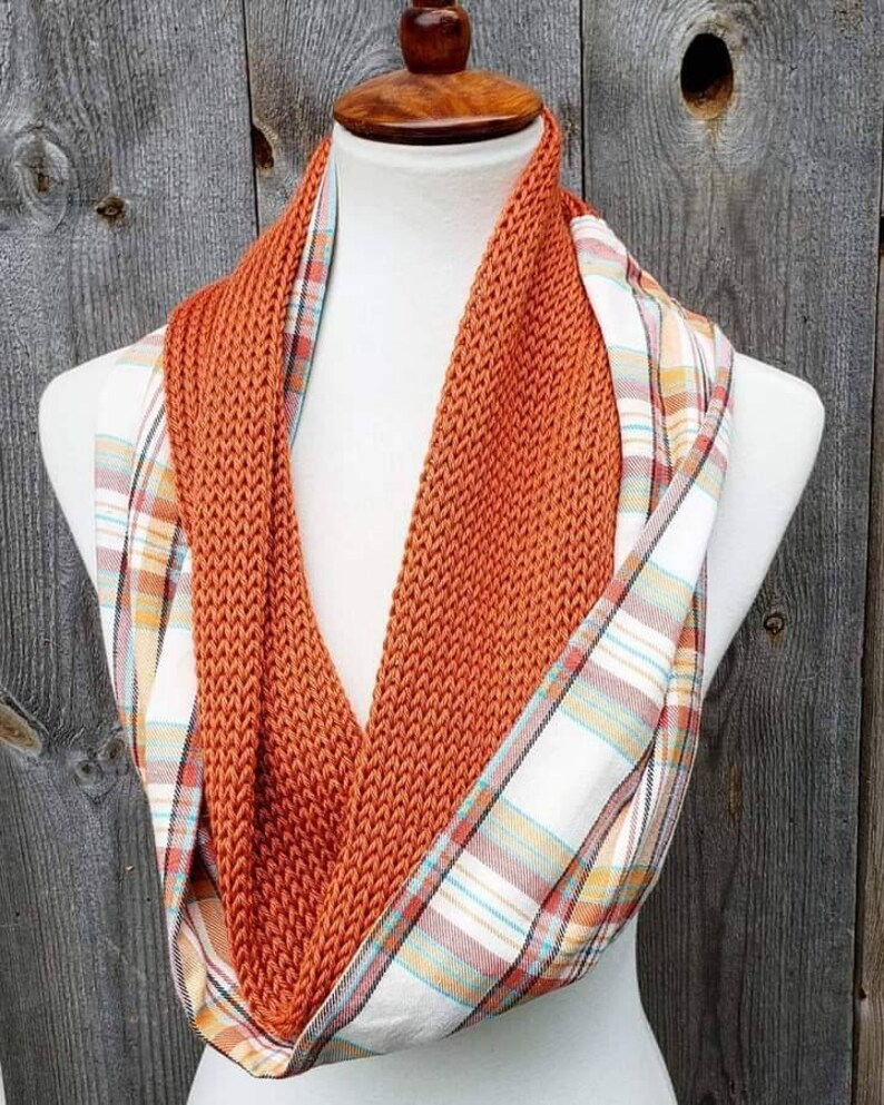 May include: A reversible scarf with a knitted orange side and a plaid side with orange, white, and blue accents.