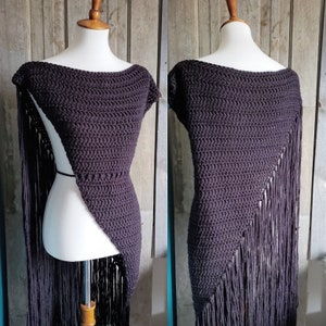 May include: A black crochet shawl with fringe detailing. The shawl is draped over a mannequin and has a triangular shape.