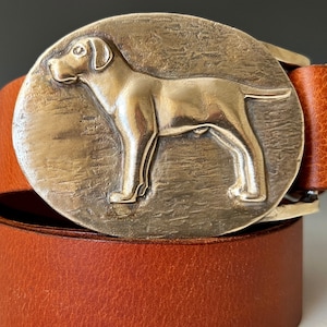 May include: A brown leather belt with a silver buckle featuring a detailed dog silhouette.