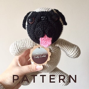 May include: Crocheted pug amigurumi toy with a pink tongue, black eyes, and a brown tag that says "McCloy's Crafty Crochet".