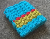 Crochet baby blanket in red, green and blue. Ideal new baby gift.