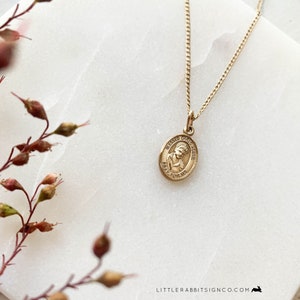 May include: Gold chain necklace with a gold oval pendant featuring a depiction of Blessed Carlo Acutis and the text "Blessed Carlo Acutis Pray for Us".