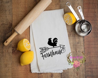 May include: White farmhouse kitchen towel with a black rooster and arrow design, with the word "Farmhouse". The image also includes a wooden rolling pin, yellow lemons, and measuring cups.