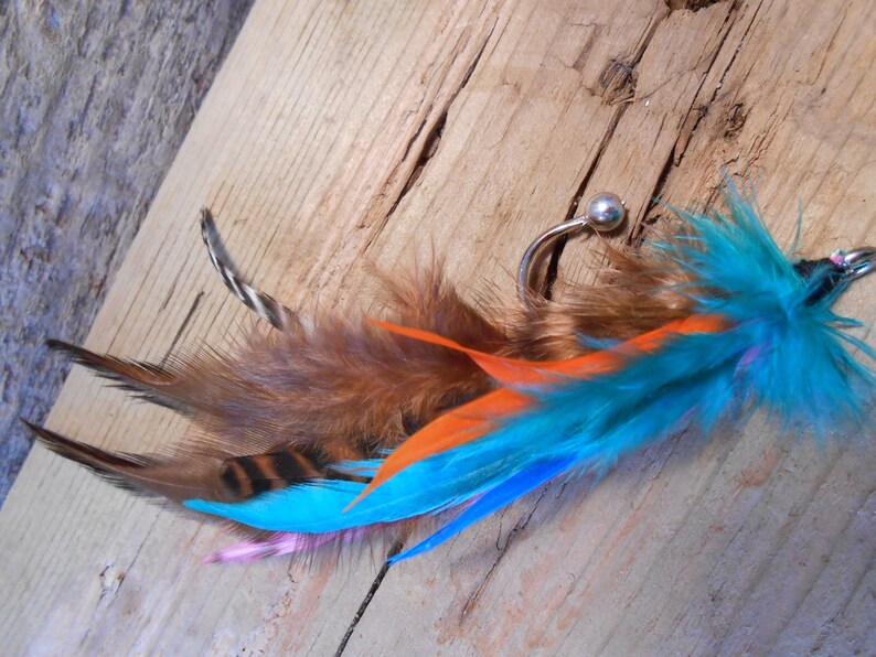 May include: A turquoise, orange, and brown feather earring with a silver hoop and a small bead.