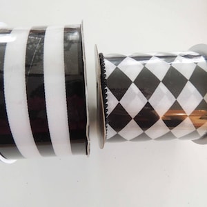 May include: Two rolls of black and white ribbon. One roll has black and white stripes, the other has a black and white checkered pattern.