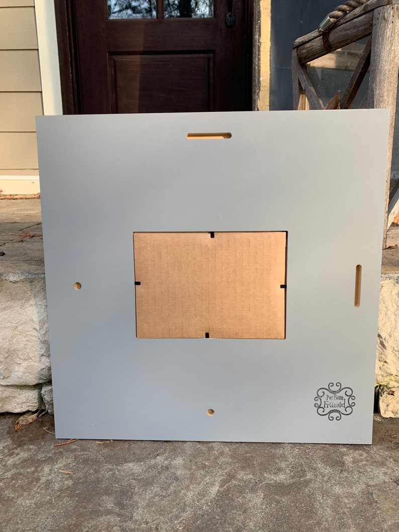 May include: A gray wooden picture frame with a brown cardboard insert. The frame has a small hole in the bottom right corner and the text "For Barn Framed" is printed in the bottom right corner.