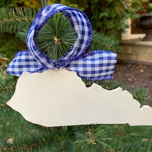 May include: White wooden ornament shaped like the state of Kentucky, decorated with a blue and white gingham ribbon.