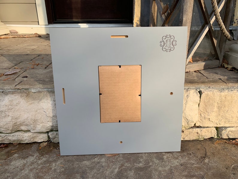 May include: A gray wooden picture frame with a cutout for a photo. The frame has a small logo in the top right corner that says "The Home Depot".