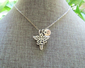May include: Silver necklace with a medical caduceus charm with the letters "SEP" and a small round charm with the letter "K".