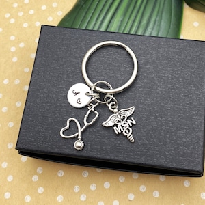 May include: Silver keychain with a stethoscope, heart, and a caduceus charm with the letters "MSN". The keychain also has a small round charm with the letter "A" and a heart.