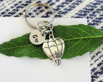 Keychain with the word serene stamped on a washer with hot air balloon charm and green crystal.