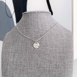 May include: A silver necklace with a hammered circular pendant.