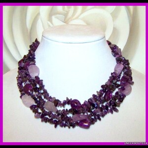 May include: A multi-strand necklace made of amethyst and rose quartz stones. The necklace is made of small, irregular shaped stones and features larger, oval-shaped stones.