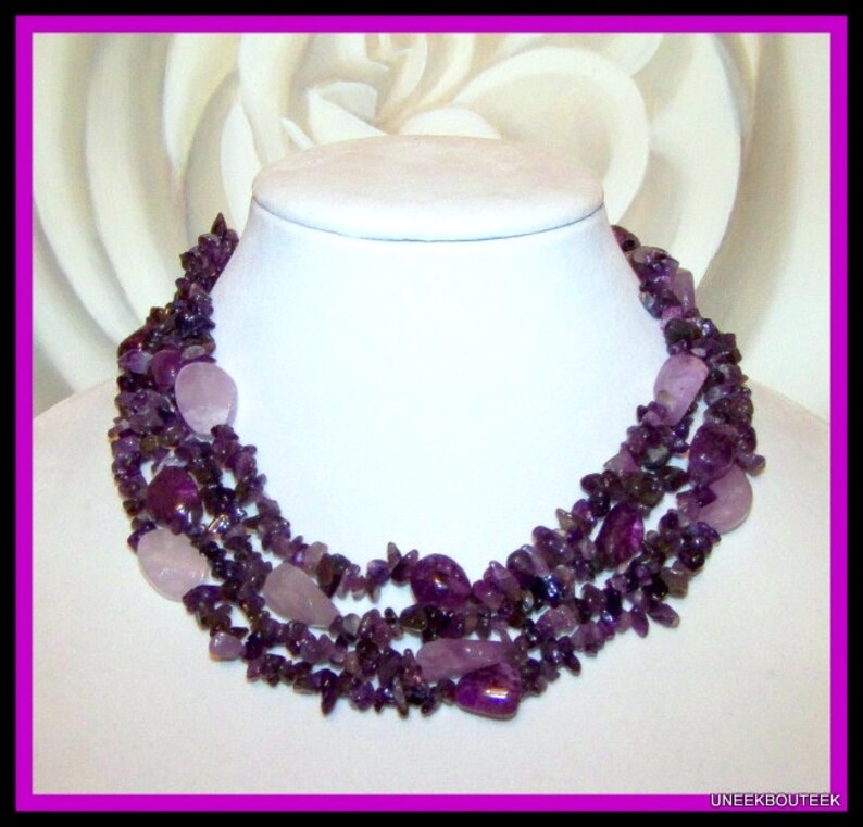 May include: A multi-strand necklace made of amethyst and rose quartz stones. The necklace is made of small, irregular shaped stones and features larger, oval-shaped stones.