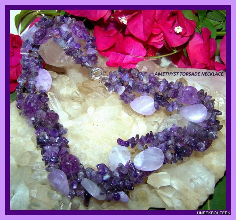 May include: A multi-strand amethyst necklace with a silver clasp. The necklace is made of small, irregular amethyst chips and larger, smooth amethyst stones. The necklace is displayed on a bed of white crystals.