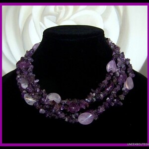 May include: A multi-strand necklace made of amethyst gemstones. The necklace is made of small, irregular shaped stones and larger, oval-shaped stones. The necklace is a deep purple color.