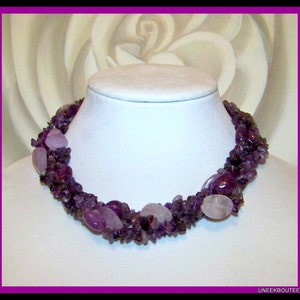 May include: A multi-strand necklace made of purple amethyst and rose quartz stones. The necklace is made of various sizes and shapes of stones, and is a beautiful and unique piece of jewelry.