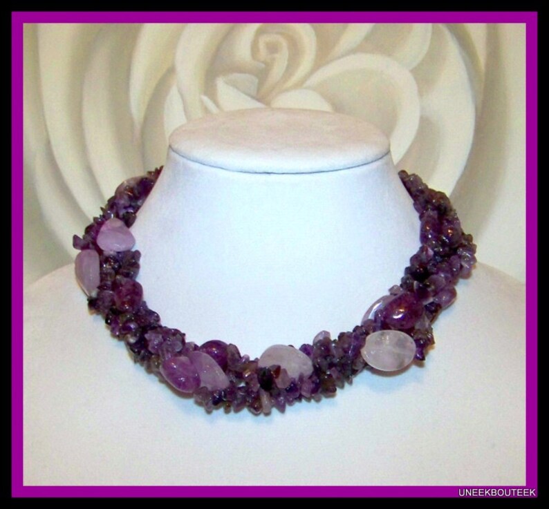 May include: A multi-strand necklace made of purple amethyst and rose quartz stones. The necklace is made of various sizes and shapes of stones, and is a beautiful and unique piece of jewelry.