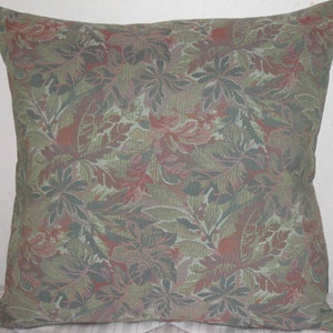May include: A green and red patterned throw pillow with a floral design. The pillow is made of a soft, textured fabric.