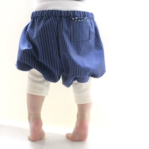May include: A child wearing blue and white striped bubble shorts with white leggings.