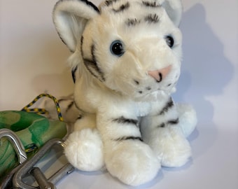 Pode incluir: Brinquedo de pelúcia de filhote de tigre branco com listras pretas. O brinquedo tem olhos azuis e um nariz rosa.