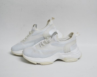 May include: A pair of white mesh sneakers with a chunky white sole. The sneakers have a lace-up closure and a slightly pointed toe.