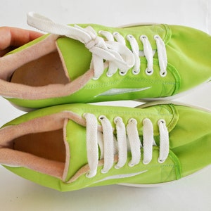 May include: A pair of lime green canvas sneakers with white laces. The shoes have a white sole and a pink lining.