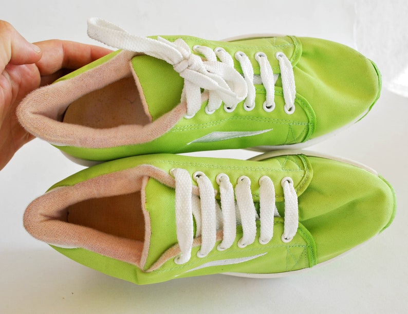 May include: A pair of lime green canvas sneakers with white laces. The shoes have a white sole and a pink lining.