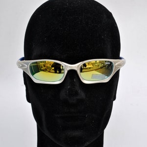 May include: Silver-framed sunglasses with gold mirrored lenses. The sunglasses are on a black mannequin head.