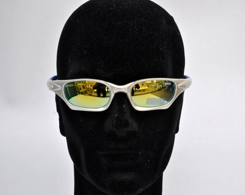 May include: Silver-framed sunglasses with gold mirrored lenses. The sunglasses are on a black mannequin head.