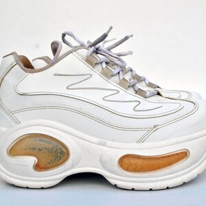 Puede incluir: Zapatillas blancas de plataforma con suela gruesa y cierre de cordones blanco.