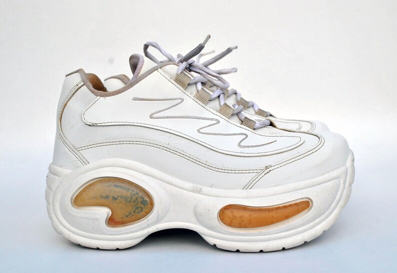 Puede incluir: Zapatillas blancas de plataforma con suela gruesa y cierre de cordones blanco.